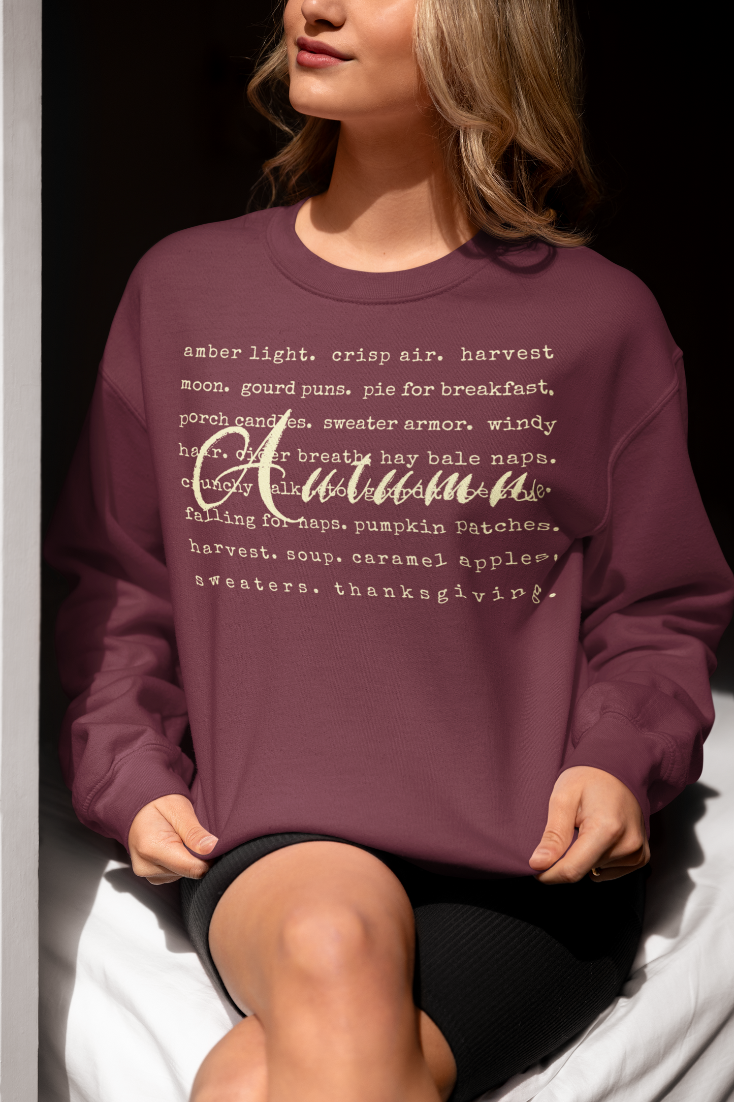 Person wearing a purple sweatshirt with 'Autumn' text, sitting on a white surface.