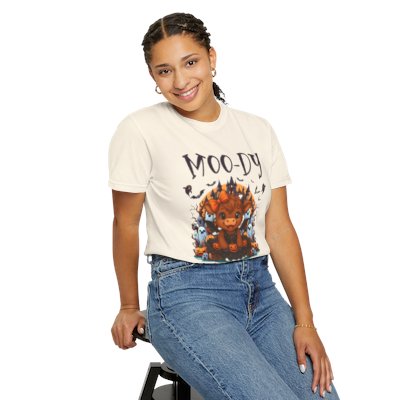 Person wearing a t-shirt with a graphic design and text, sitting on a stool against a white background