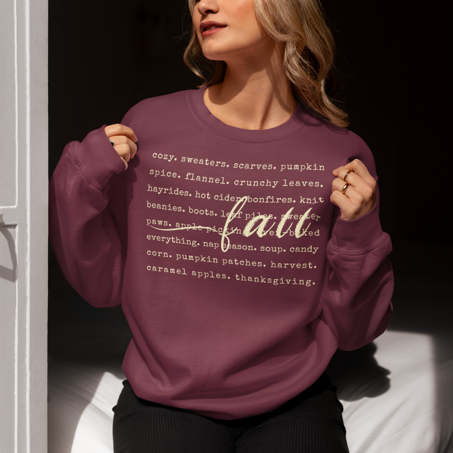 Person wearing a maroon sweatshirt with 'fall' text on a dark background