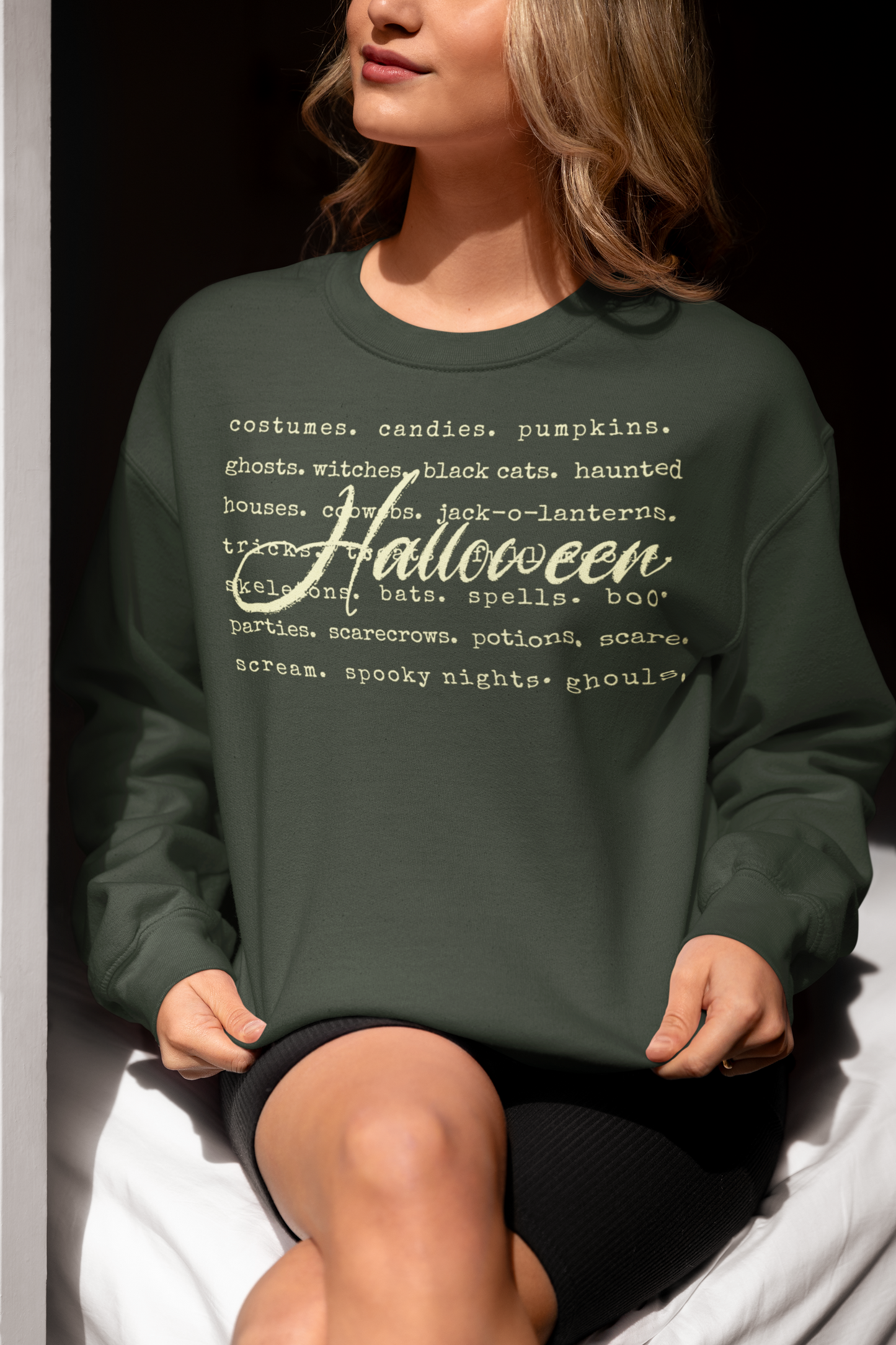 Person wearing a green sweatshirt with Halloween-themed text.