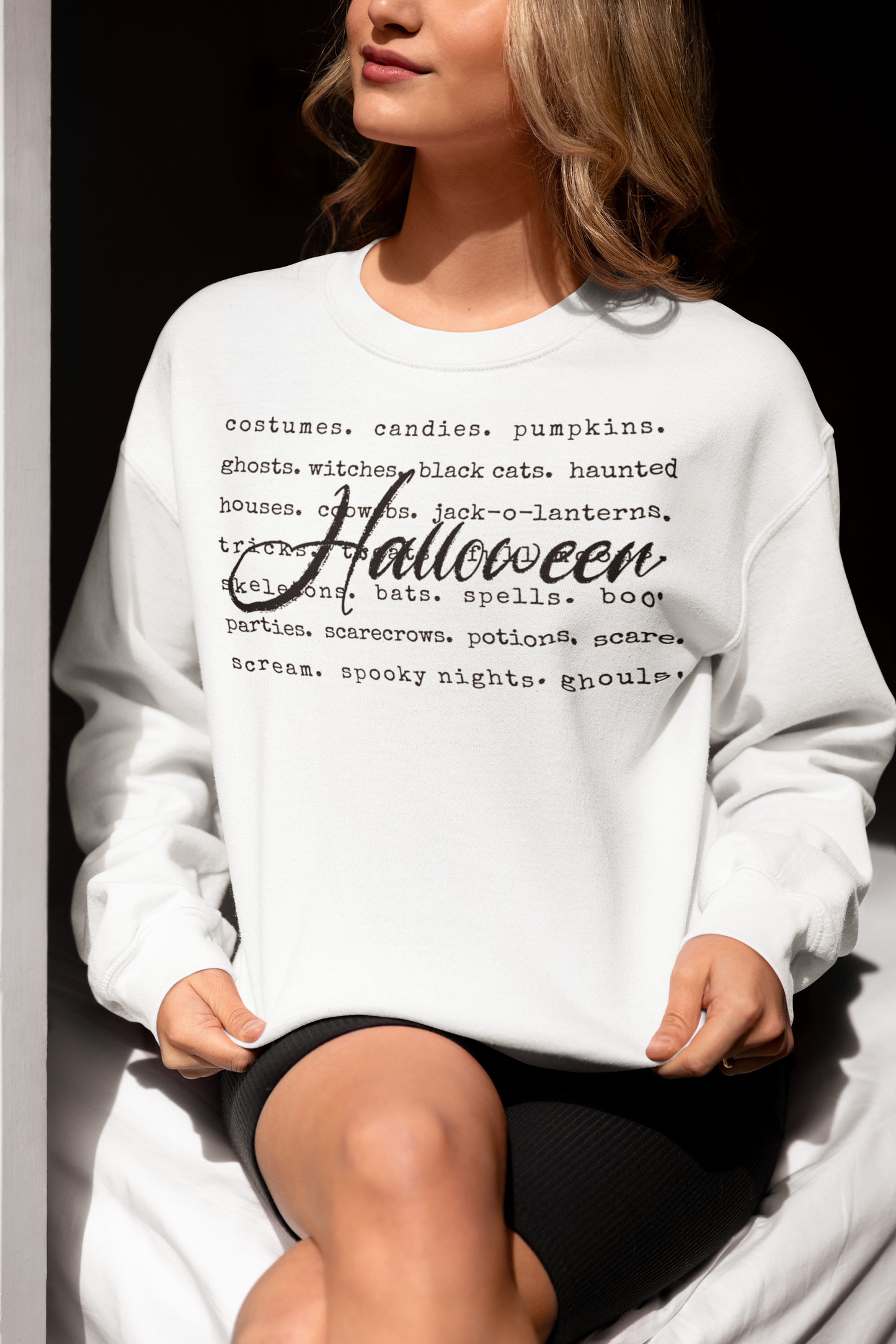Person wearing a white sweatshirt with Halloween-themed text design.