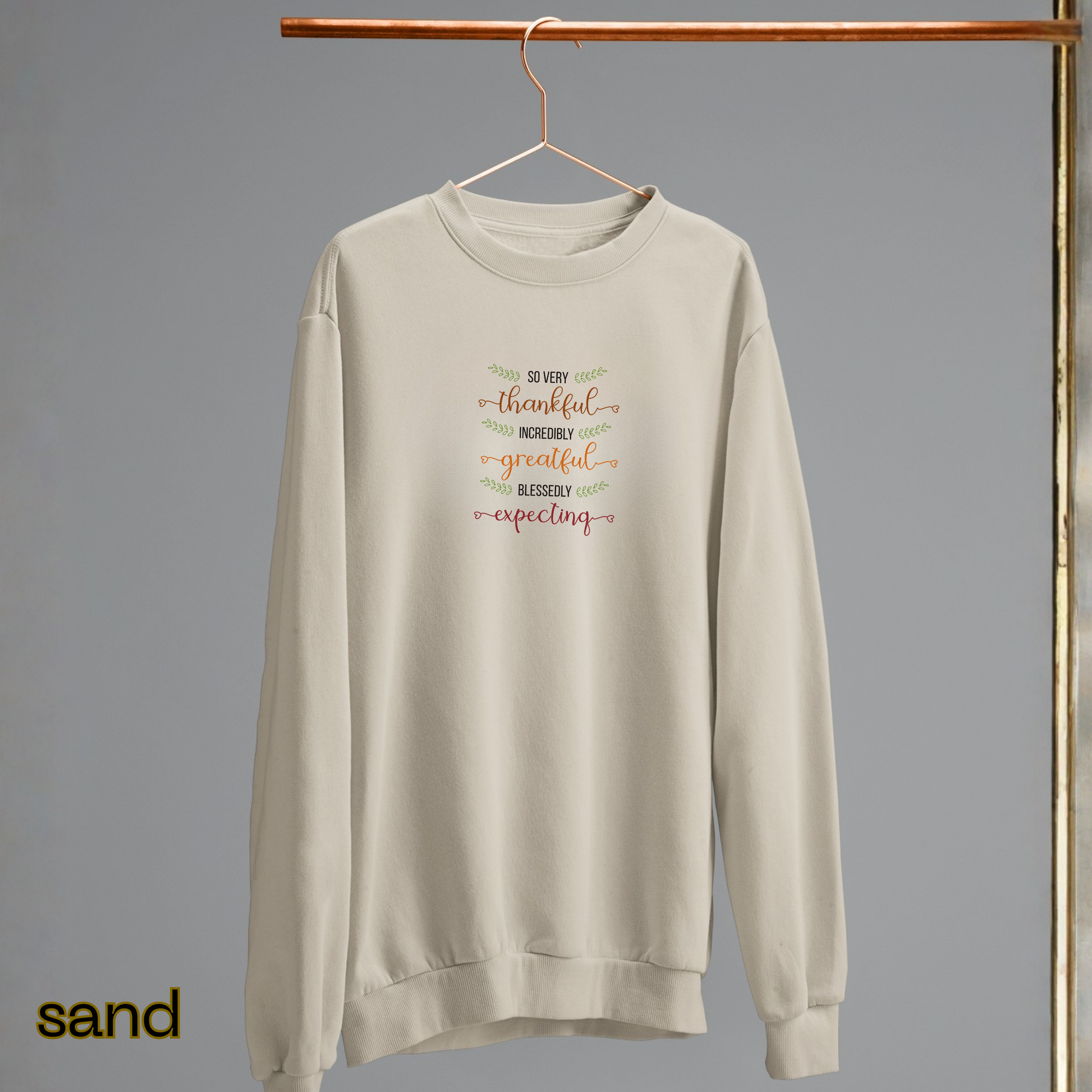 Beige sweatshirt with text on a hanger against a gray background