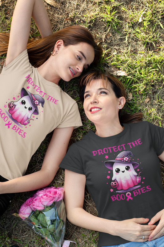 Mom and daughter lying on grass wearing t-shirts with ghost and pink ribbon designs.