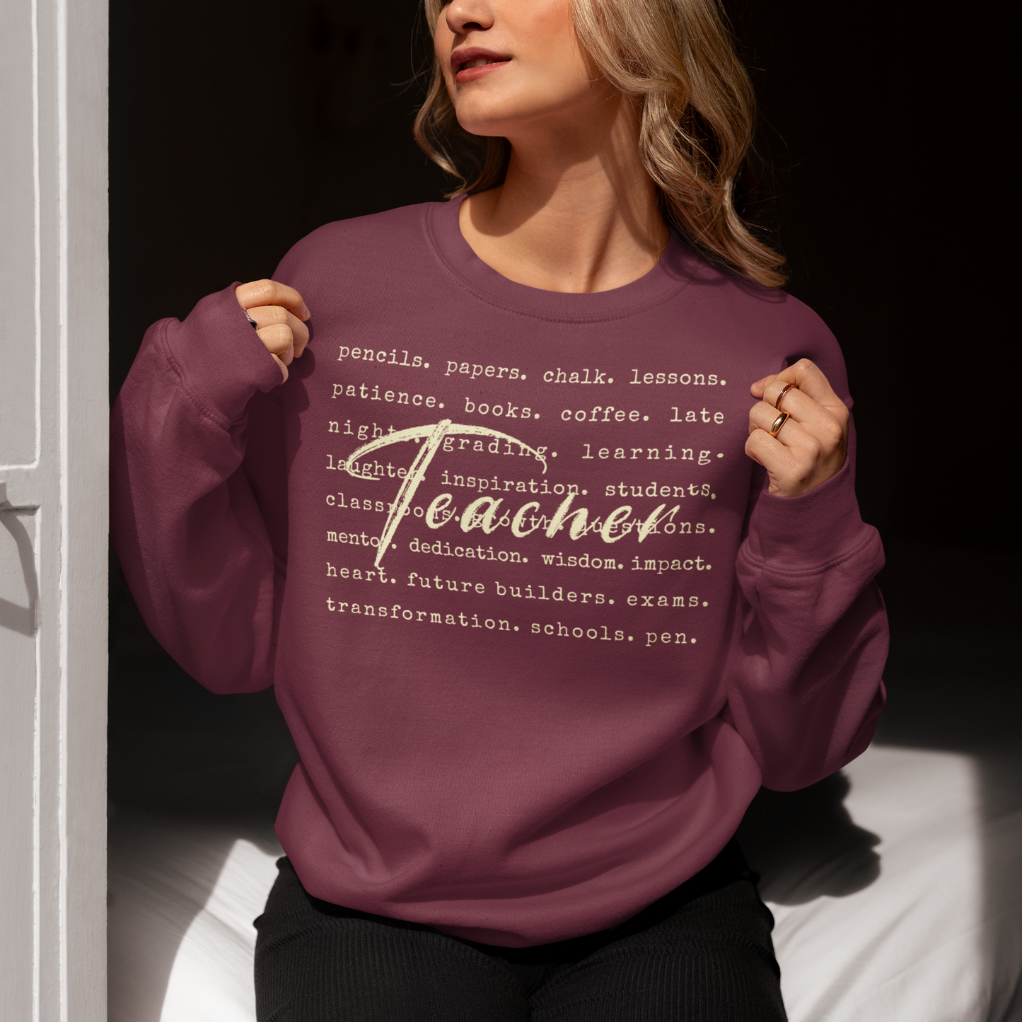 Person wearing a maroon sweatshirt with text design, sitting indoors.