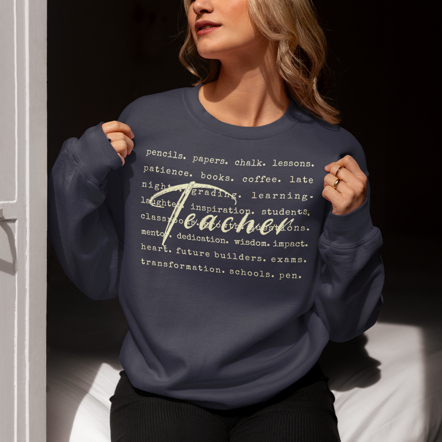 Person wearing a navy blue sweatshirt with text design, sitting indoors.