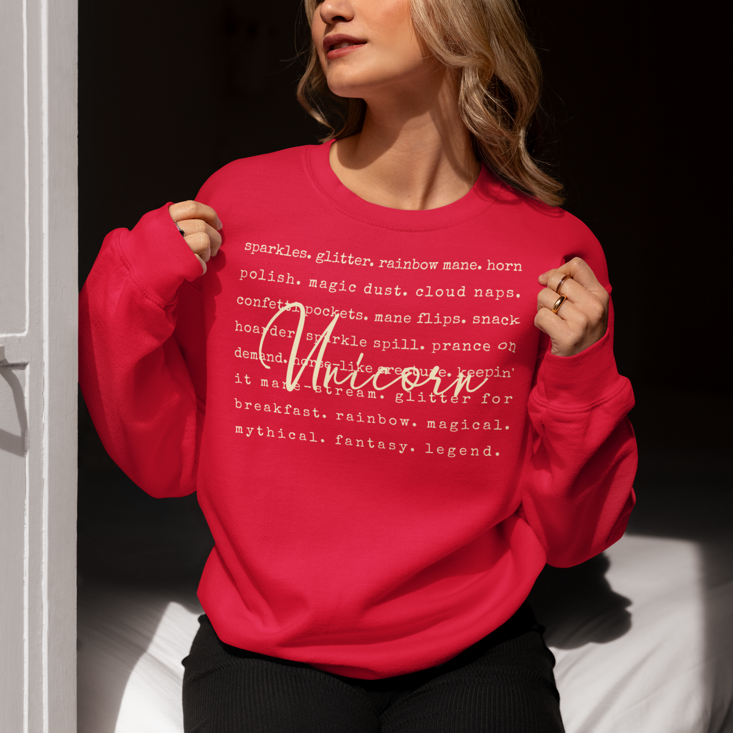 Person wearing a red sweatshirt with text and the word 'Unicorn' on it, against a dark background.