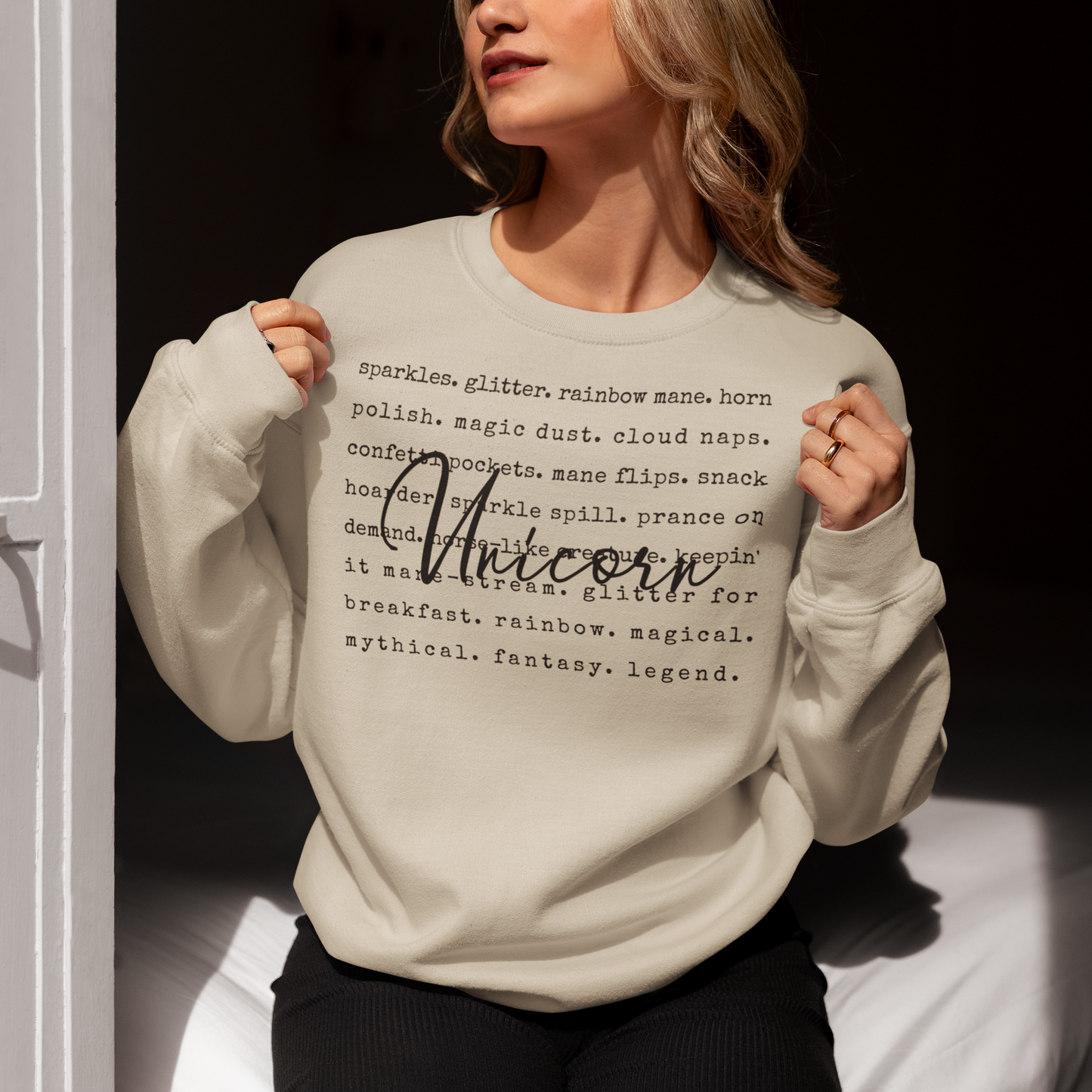 Person wearing a light gray sweatshirt with text and the word 'Unicorn' printed on it.